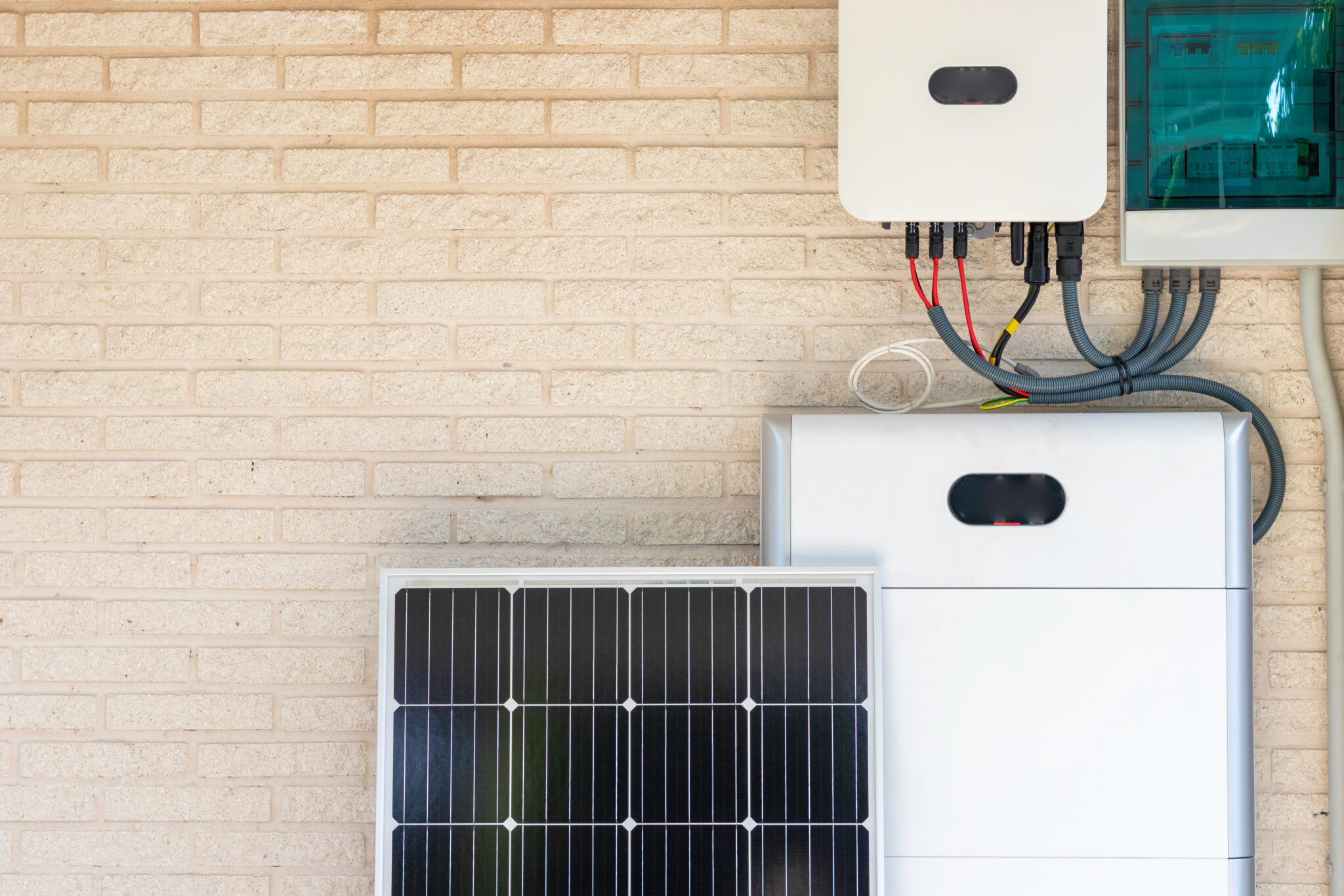 Front view of photovoltaic panel and battery instalation leaning on the beige white wall with no people. Renewable energy concept